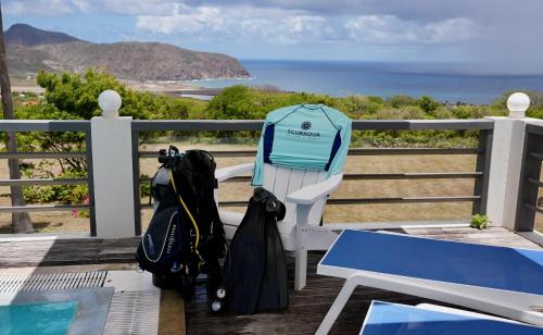 a bench with two umbrellas sitting next to the ocean at Quill Gardens Boutique Hotel in Oranjestad