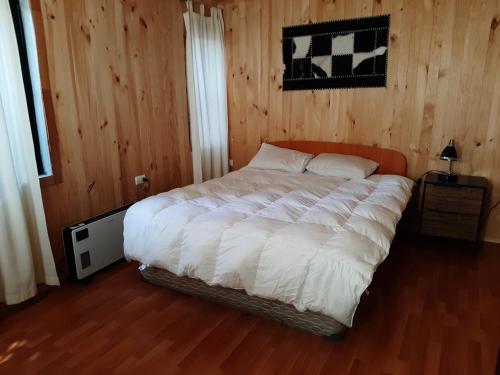 1 dormitorio con 1 cama blanca grande y paredes de madera en Wool & Wood House en Puerto Varas