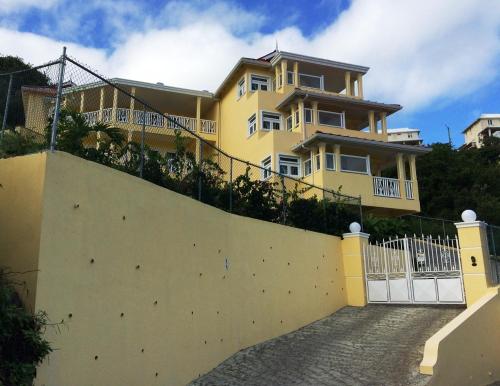 a yellow house with a white fence in front of it at South Sea House in Cap Estate