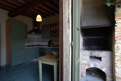 a kitchen with a brick fireplace with a table in it at Podere Il Pino in Poggibonsi
