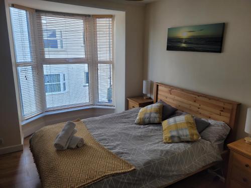 a bedroom with a bed with two pillows and two windows at Large 5 bed town-centre home close to the beach, sleeps 9 in Aberystwyth