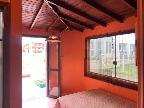 um quarto com paredes cor de laranja, uma janela e uma cama em Residencial dos Moleques em Capão da Canoa