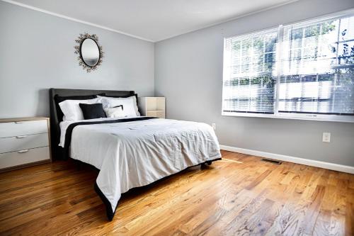 ein Schlafzimmer mit einem Bett, einem Spiegel und einem Fenster in der Unterkunft Urban Oasis Spacious 3BR 2BA Patio Near NYC EWR American Dream Mall in Newark