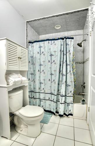 a bathroom with a toilet and a shower curtain at Urban Oasis Spacious 3BR 2BA Patio Near NYC EWR American Dream Mall in Newark