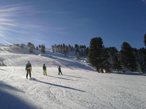 three people are skiing down a snow covered slope at Gasthof Trattner Pension Waldhof in Sankt Peter am Kammersberg