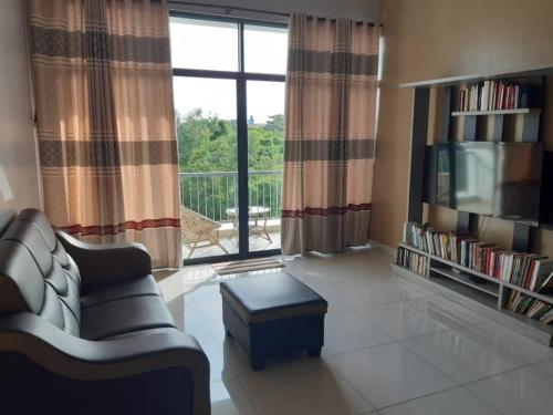 a living room with a couch and a large window at Labuan Paragon Apartment - 3 rooms in Labuan
