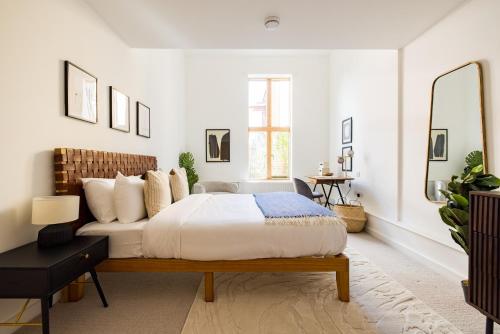 a white bedroom with a bed and a mirror at The Clapham Dream - Captivating 3BDR with Garden & Parking in London