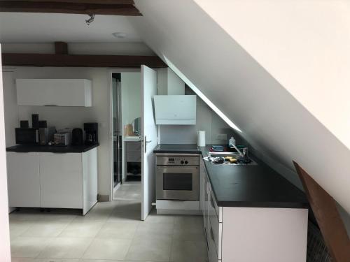 une cuisine avec des placards blancs et un escalier dans l'établissement Résidence Merlin Appart des Druides, à Saint-Malon-sur-Mel