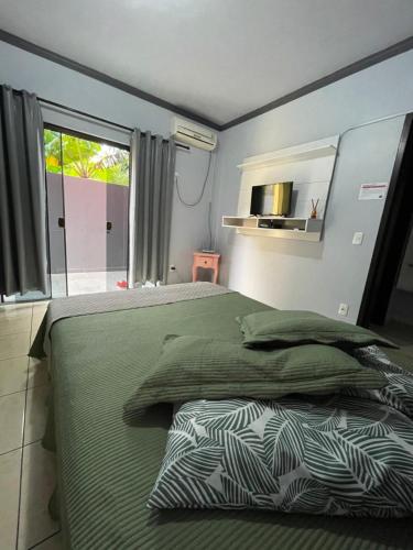a bedroom with a bed with green sheets and a window at Encanto Parque Pousada in Penha