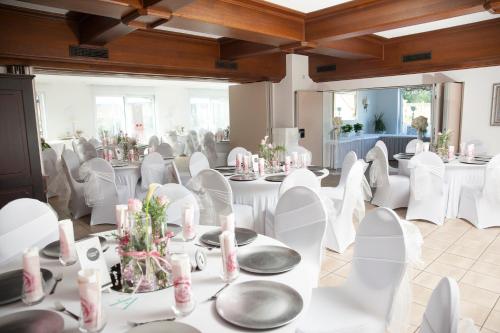 a banquet hall with white tables and white chairs at Zur Linde in Mainzweiler