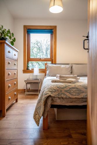 a bedroom with a bed with a dresser and a window at Coorie View in Kilmore