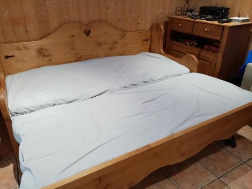 a bed with white sheets and a wooden headboard at quereuilh in Le Mont-Dore