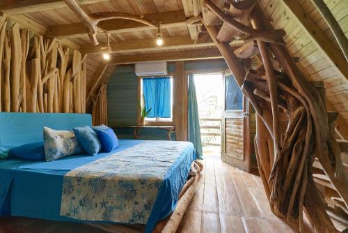 um quarto com uma cama azul num chalé de madeira em CHALET TROPICAL Hotel & Restaurante em Las Galeras