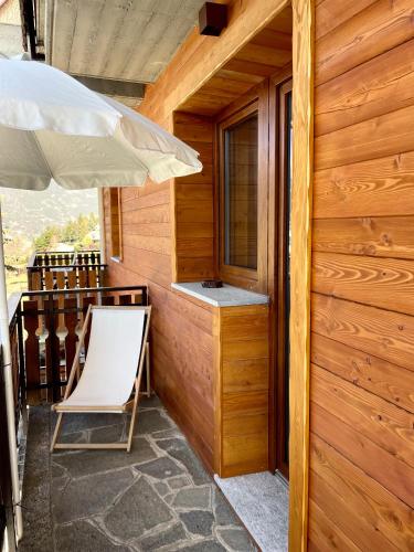 a porch with a white chair and an umbrella at Case Vacanza Perron in Sauze dʼOulx