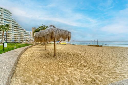 a beach with a straw umbrella on the sand at Bay Dream 2B W/Wifi, Grill & View. in San Antonio