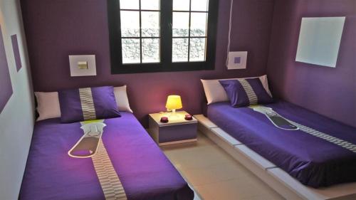 2 Betten in einem Zimmer mit lila Wänden in der Unterkunft Villa Celeste in Playa Blanca
