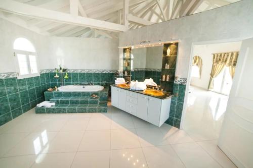 a bathroom with green tile and a tub and a sink at Villa Millésime in Le François