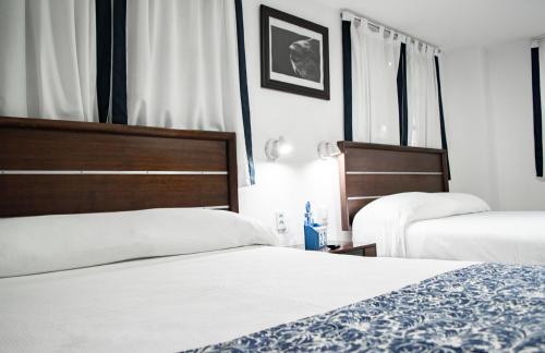 two beds in a hotel room with white sheets at Hotel Rio Atlixco in Atlixco