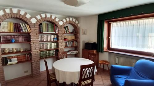 a room with a table and chairs and bookshelves at Casa Gonano in Prato Carnico