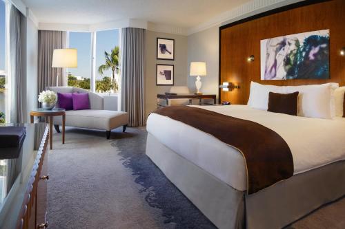 a hotel room with a large bed and a chair at Pullman Miami Airport in Miami