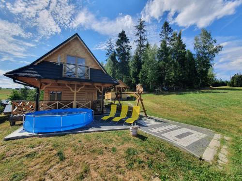 uma cabana de madeira com um parque infantil e uma casa em Domek w górach pod Jodłami em Nowy Targ