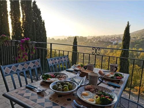 a table with plates of food on top of a balcony at GLI ALBERI apartment with view in Montepulciano