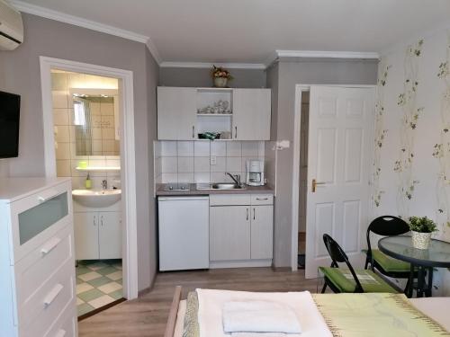 een keuken met witte kasten, een tafel en een wastafel bij Veronika Villa in Balatonfüred