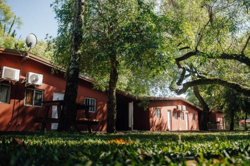 a red building with trees in front of it at Cabañas Los Timbó in Ituzaingó
