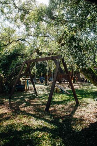 a wooden swing set in a park under a tree at Cabañas Los Timbó in Ituzaingó