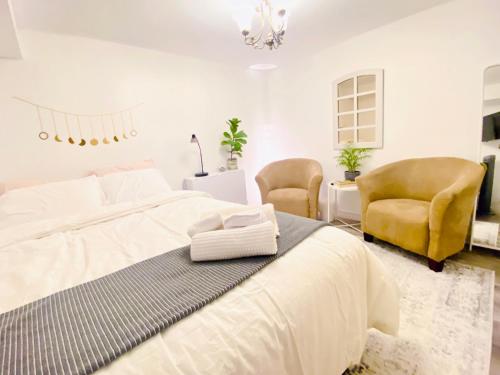 a white bedroom with a large bed and two chairs at Sunrise Tree BnB - your Home away from home in Toronto