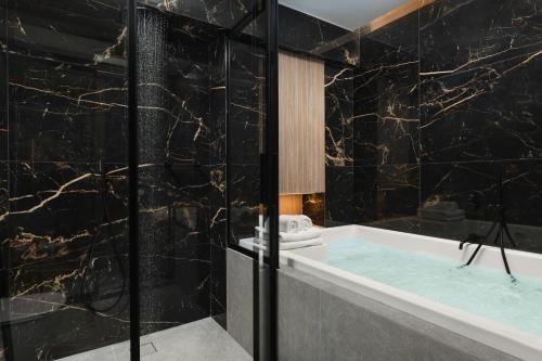 a bathroom with a tub and black marble walls at Urban Lofts in Chania