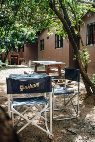 a picnic table and two chairs under a tree at Cabañas Los Timbó in Ituzaingó