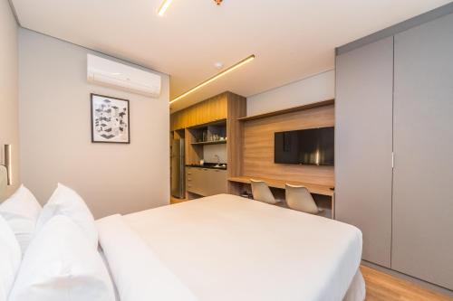 a bedroom with a white bed and a tv at Charlie Domy Paraíso in São Paulo