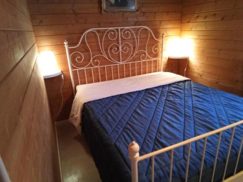 Ce lit se trouve dans un dortoir en bois doté de 2 lampes. dans l'établissement casa ginefra, à Tito