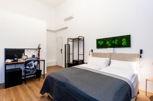 a bedroom with a bed and a desk with a computer at Adagio Downtown Rooms in Budapest
