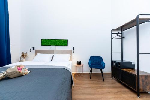 ein Schlafzimmer mit einem Bett und einem blauen Stuhl in der Unterkunft Adagio Downtown Rooms in Budapest