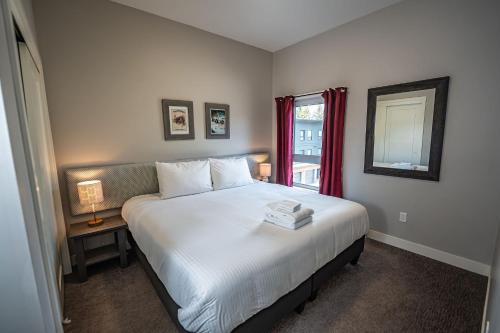 a bedroom with a large white bed with a window at Pillow Top Condo by Revelstoke Vacations in Revelstoke