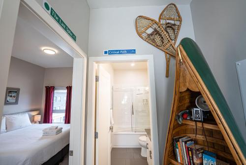 a bedroom with a bed and a bathroom with a book shelf at Pillow Top Condo by Revelstoke Vacations in Revelstoke