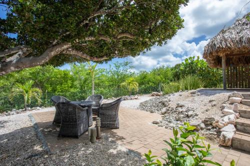 a patio with two wicker chairs under a tree at Villa Caribbean Passion in Willibrordus
