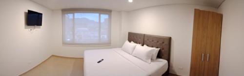 een slaapkamer met een bed met witte lakens en een raam bij Aparta Suite Plaza Premium by Tourism Yossa in Bogota