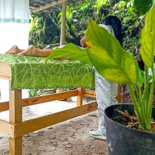 a person standing next to a bed with a plant at Ecohotel Soplo del Tambo in Cocorná