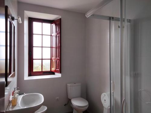 baño con aseo y lavabo y ventana en Albergue Abeiro do Sor en Mañón