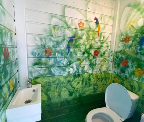 bagno con servizi igienici e un dipinto a muro di uccelli. di AZUR INDIGO, Gîtes titanse et spa a Cadet