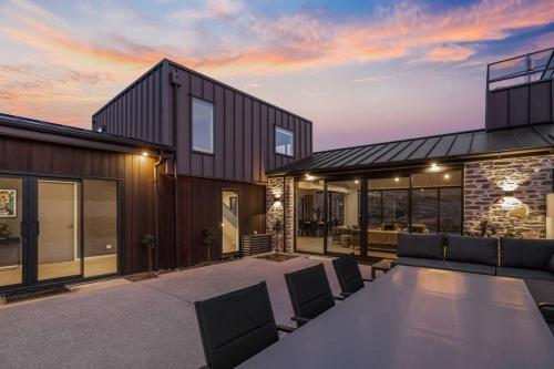 ein Haus mit einem Tisch und Stühlen auf einer Terrasse in der Unterkunft The Ultimate Dream Idyllic Brand New Alpine Home in Queenstown