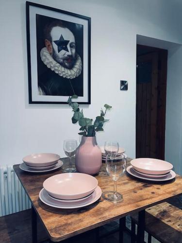 a table with plates and glasses and a picture of a man at Historic Cottage in the Heart of Old Aberdeen. in Aberdeen