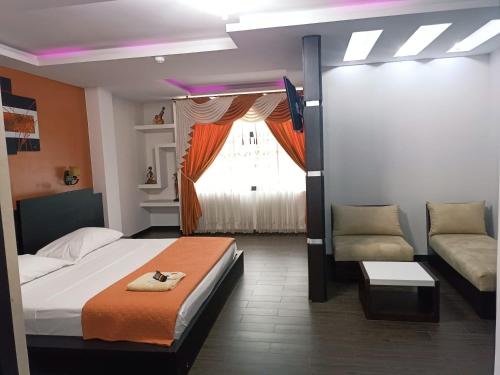 a bedroom with a bed and a couch and a window at Hotel Quezada Hermanos in Santo Domingo de los Colorados