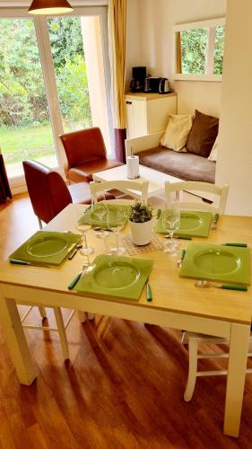 - une table en bois avec des assiettes vertes et des verres à vin dans l'établissement Gîte Bulle de détente-Aux Portes d'Honfleur avec piscine couverte, à Boulleville