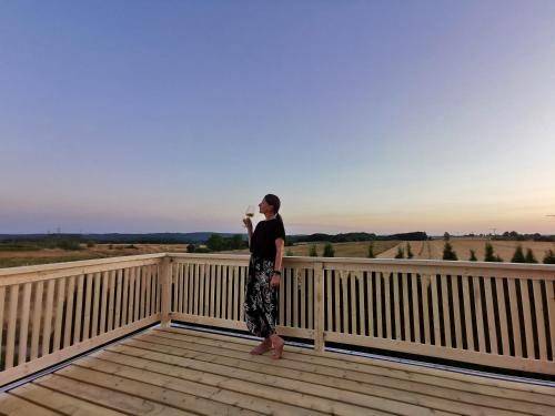 a woman standing on a wooden balcony with the sunset at BB19 Eifel-Ferienhaus am Moseltal mit Saunahaus in Beuren