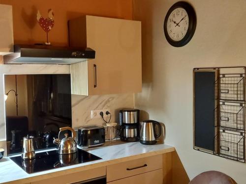 une cuisine avec des casseroles et des poêles sur un comptoir avec une horloge dans l'établissement S'gleina Gleck, in the heart of a wine city, Charmant Studio 1 pièce et 1 salle de bain, à Kaysersberg