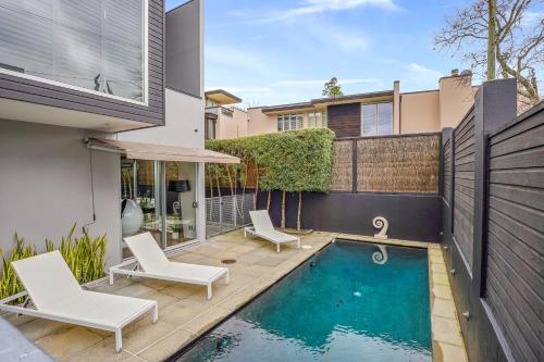 a backyard with a swimming pool and two chairs and a house at Central High-end 3BR Home in Parnell with Pool in Auckland